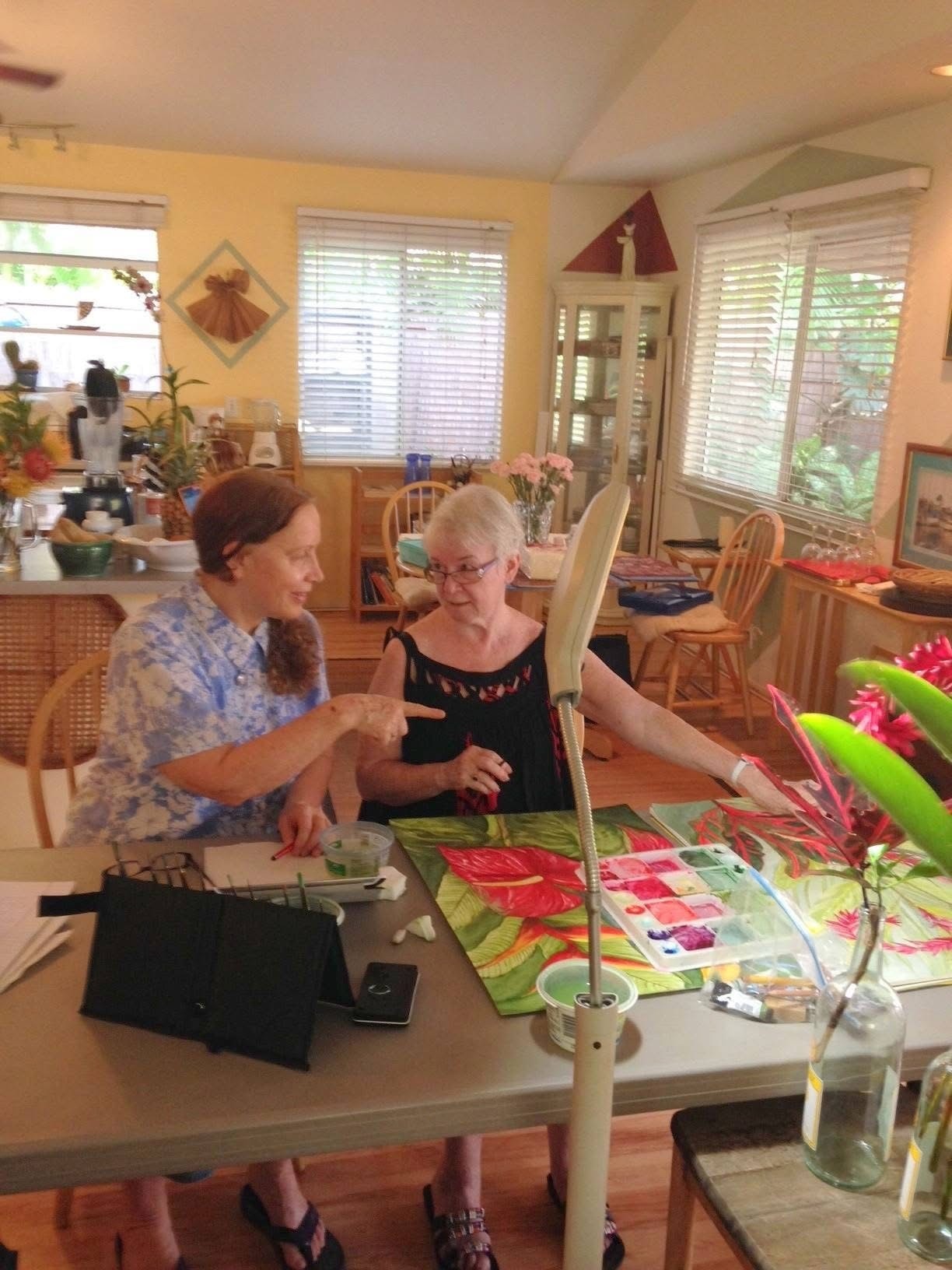 Barbara Steinberg instructing a student one-on-one during an indoor watercolor class in Maui