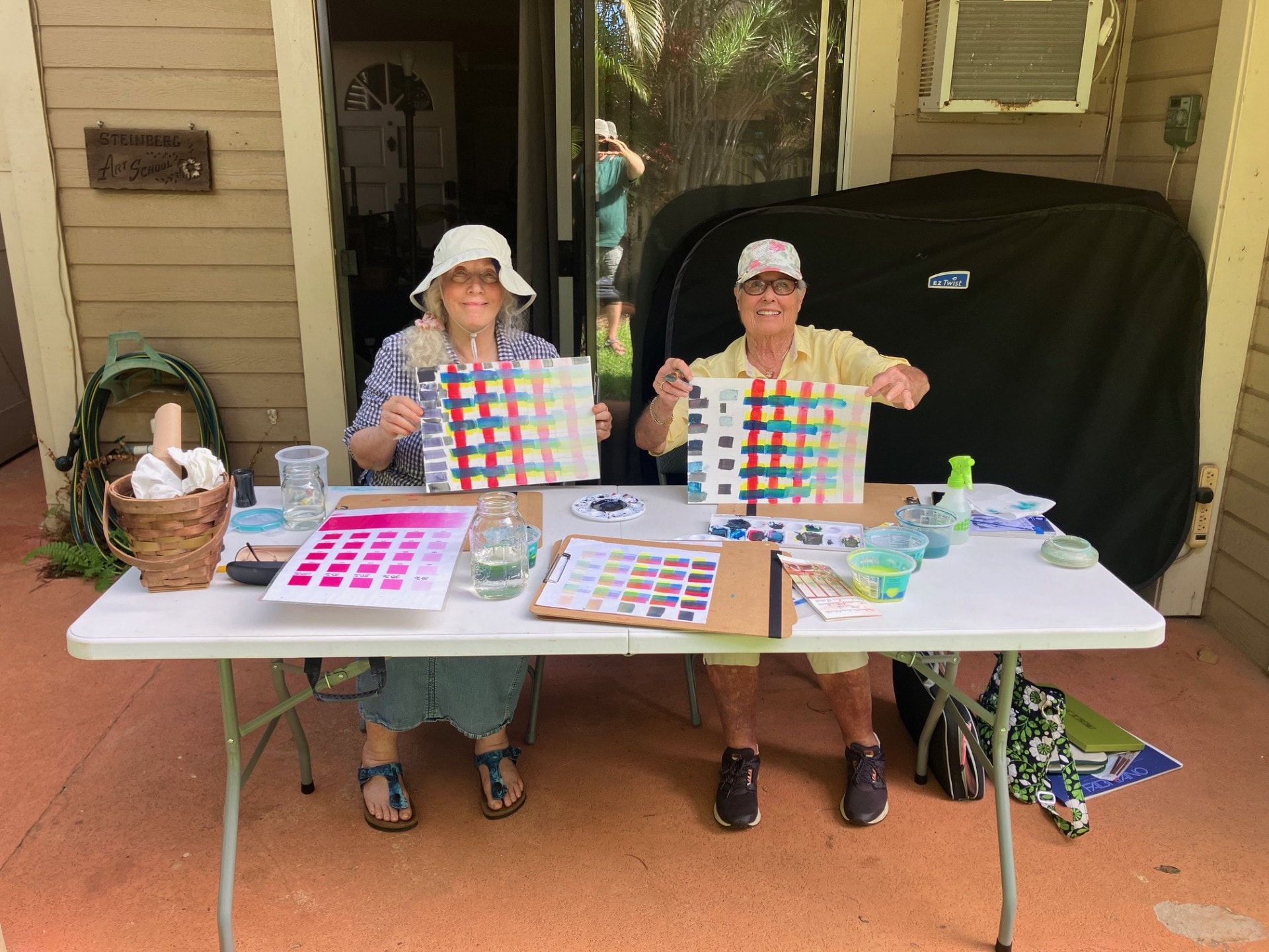 Two students displaying their color blending exercise charts at Steinberg Art School outdoor class